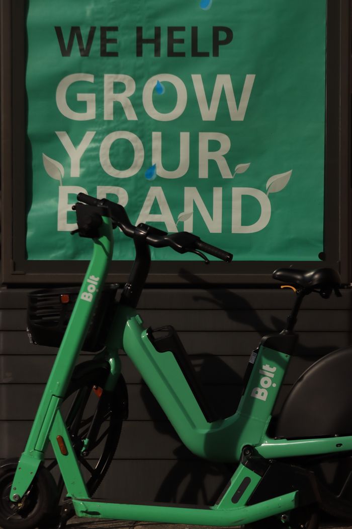 Trottinette électrique appuyée contre un mur avec un slogan de croissance de marque.